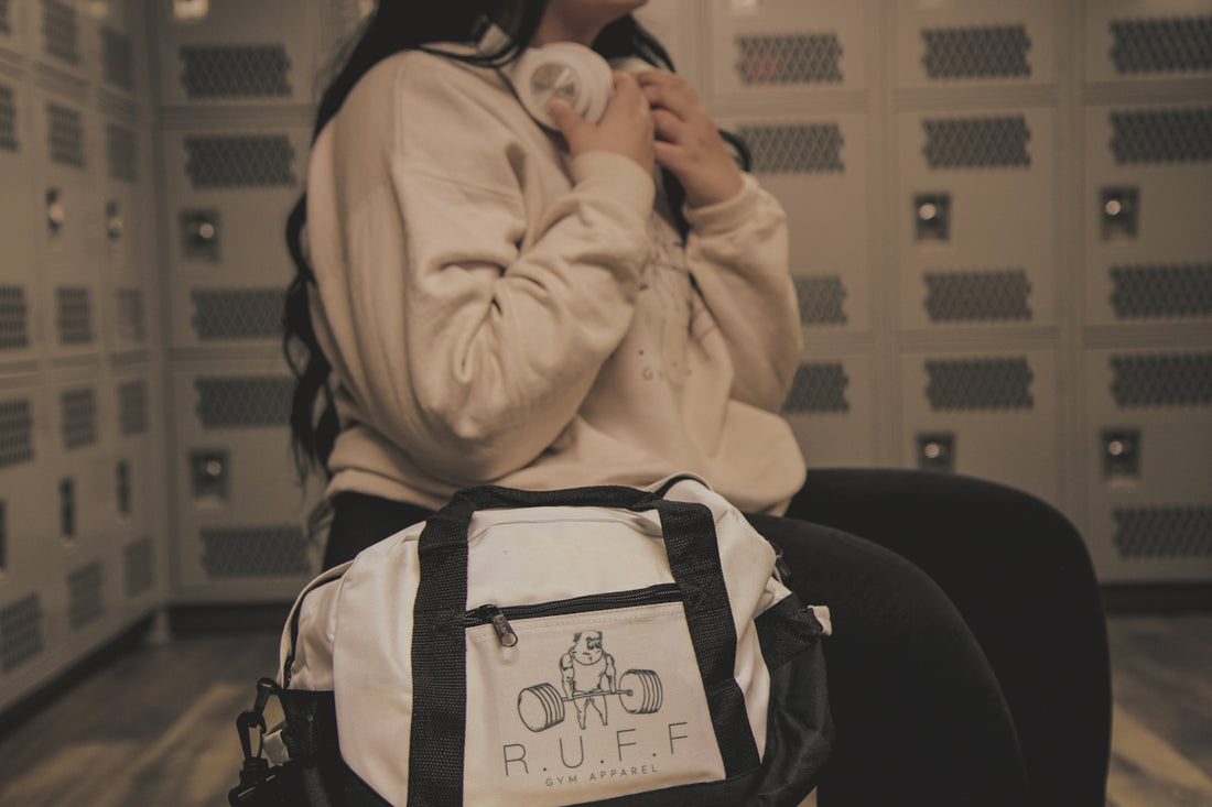 a woman sitting in a locker with a duffle bag