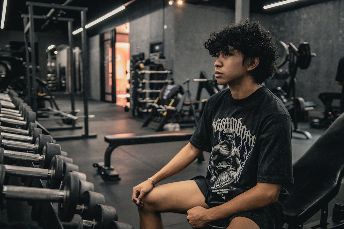 A young man sitting on a bench in a gym