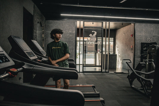 A man standing in a gym next to a row of treadmills