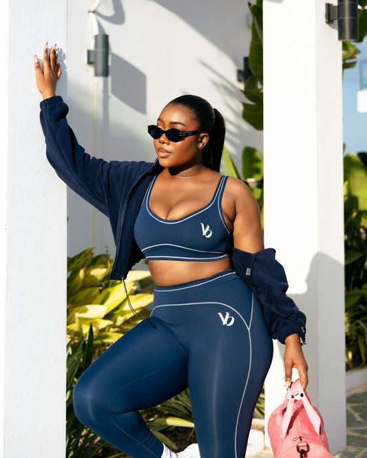 A woman in navy activewear holds a pink gym bag.