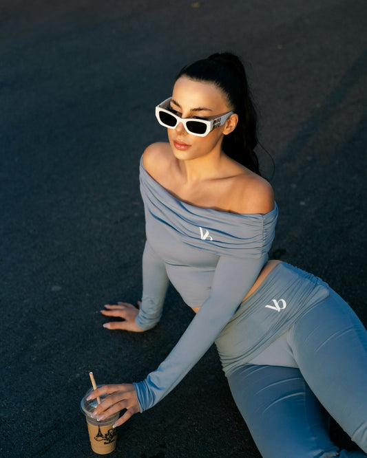 Woman in sunglasses and off-the-shoulder top with coffee