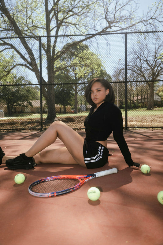 Young woman posing on tennis court with racket and racquet