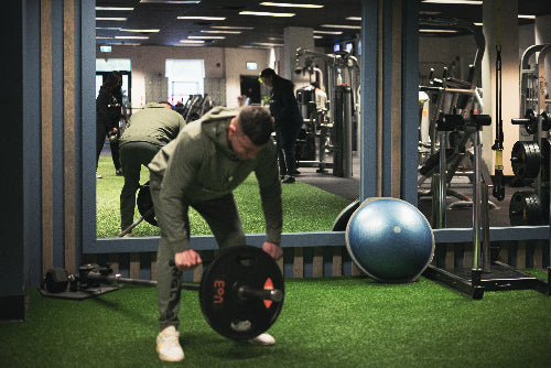 Person lifting weights in a gym with exercise ball and equipment in the background